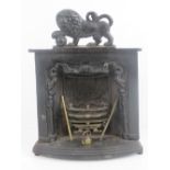 A miniature cast iron fireplace complete with integral grate and tools, lion ardent over, 27cm high.