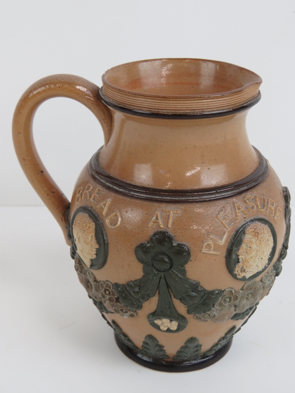 A Doulton Lambeth applied jug 'Bread at Pleasure, Drink by Measure', 12cm high.