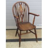 A single wheel back elm seated open armchair raised over turned legs.