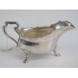 A HM silver sauce boat having pie crust edge and raised over three outswept feet,