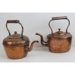 Two copper kettles each with heatproof handle.