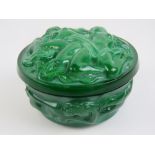 A green glass relief lidded pot decorated with nude figures throughout, 10cm diameter.