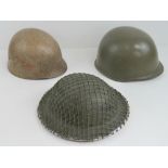 A WWII Czech helmet having green netting and replacement liner together with a WWII US helmet and a