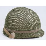 A WWII US helmet with liner, painted white and having later green netting over.