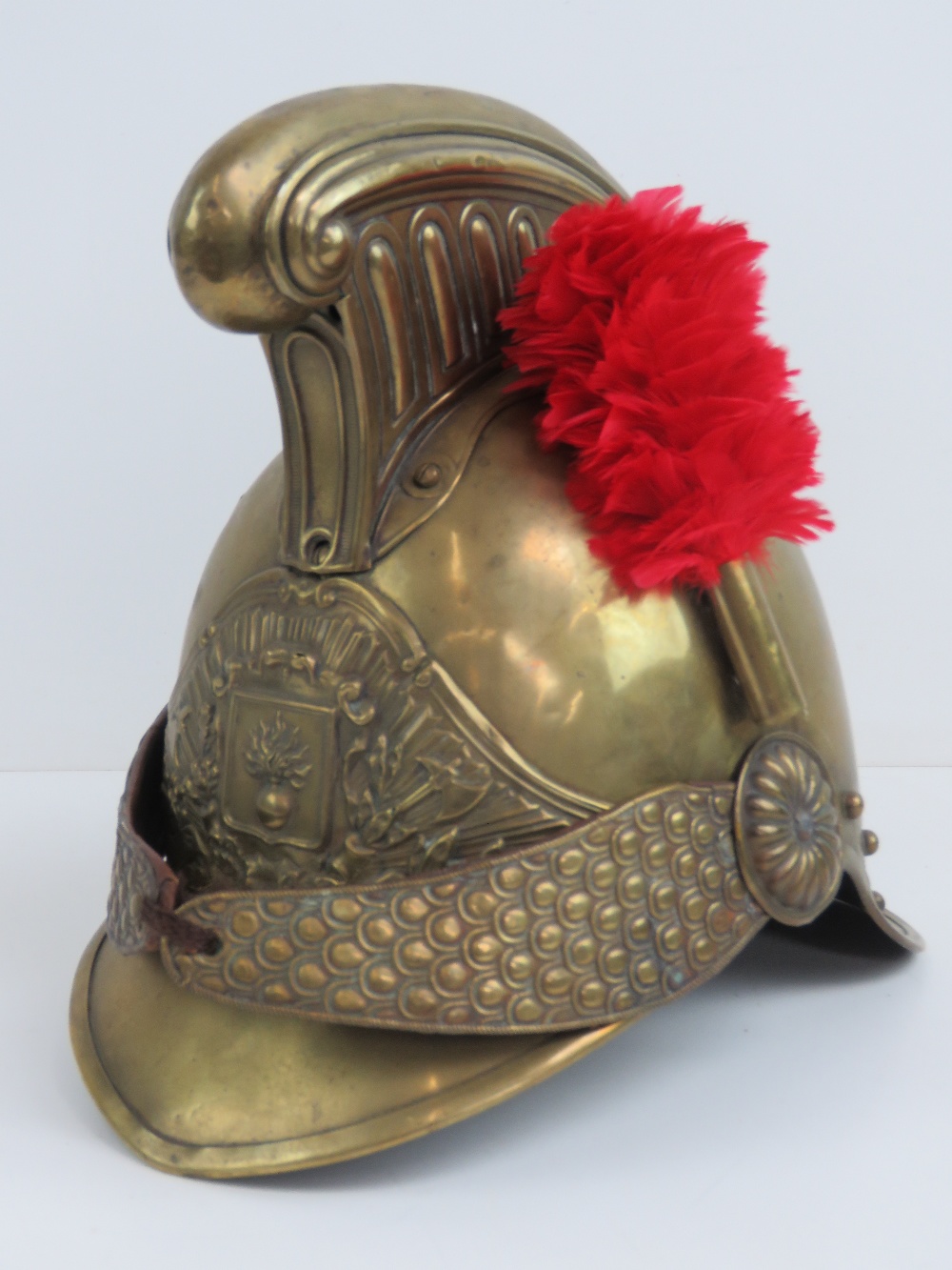 A French 19th century fireman's helmet in brass having red plume upon.