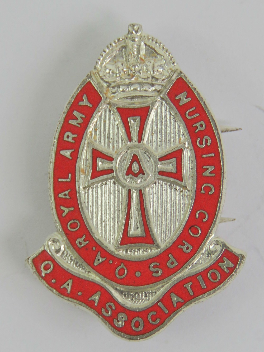 A Queen Alexandra's Royal Army Nursing Corps Association badge inlaid with red enamel, made by J.R.