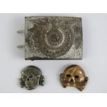A WWII German SS belt buckle together with two SS Totenkopf skull cap badges.