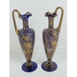 A pair of gilded and enamelled slender ewers in glass, each standing 24cm high.
