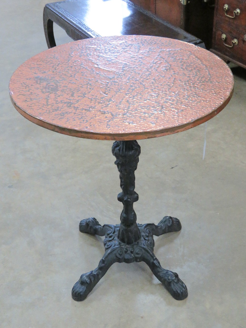 A circular beaten copper pub style table having cast iron quatreform base.