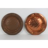 A pair of decorative planished copper plates each measuring 29cm dia. Total weight 1kg.