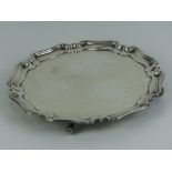 A HM silver salver having pie crust edge and raised over four scroll feet,