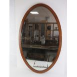 An oval Edwardian mahogany framed mirror cross-banded with walnut measuring 92 x 59cm.