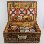 A wicker picnic basket containing plates, cutlery, table cloth etc.