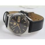 A Seiko 5 automatic wristwatch with black dial, yellow metal hands and batons,