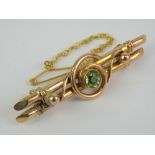 A rose metal double bar brooch having scrollwork upon and central round cut peridot approx 0.