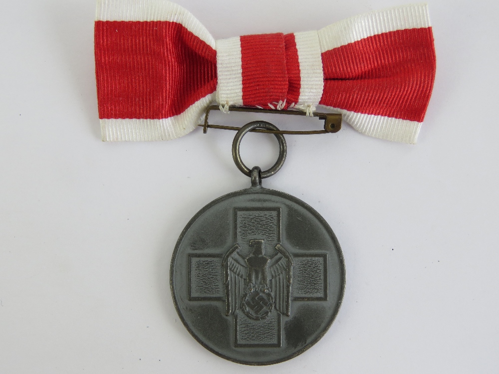 A WWII German Red Cross medal with ribbon.