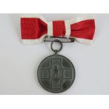 A WWII German Red Cross medal with ribbon.