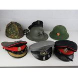 Seven assorted military hats, helmets and caps.