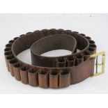 A brown leather shotgun cartridge belt in brown leather with brass buckle.