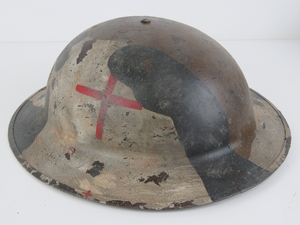 A WWII British Naval First Aid Medic helmet with camo overlay.