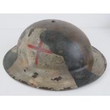 A WWII British Naval First Aid Medic helmet with camo overlay.