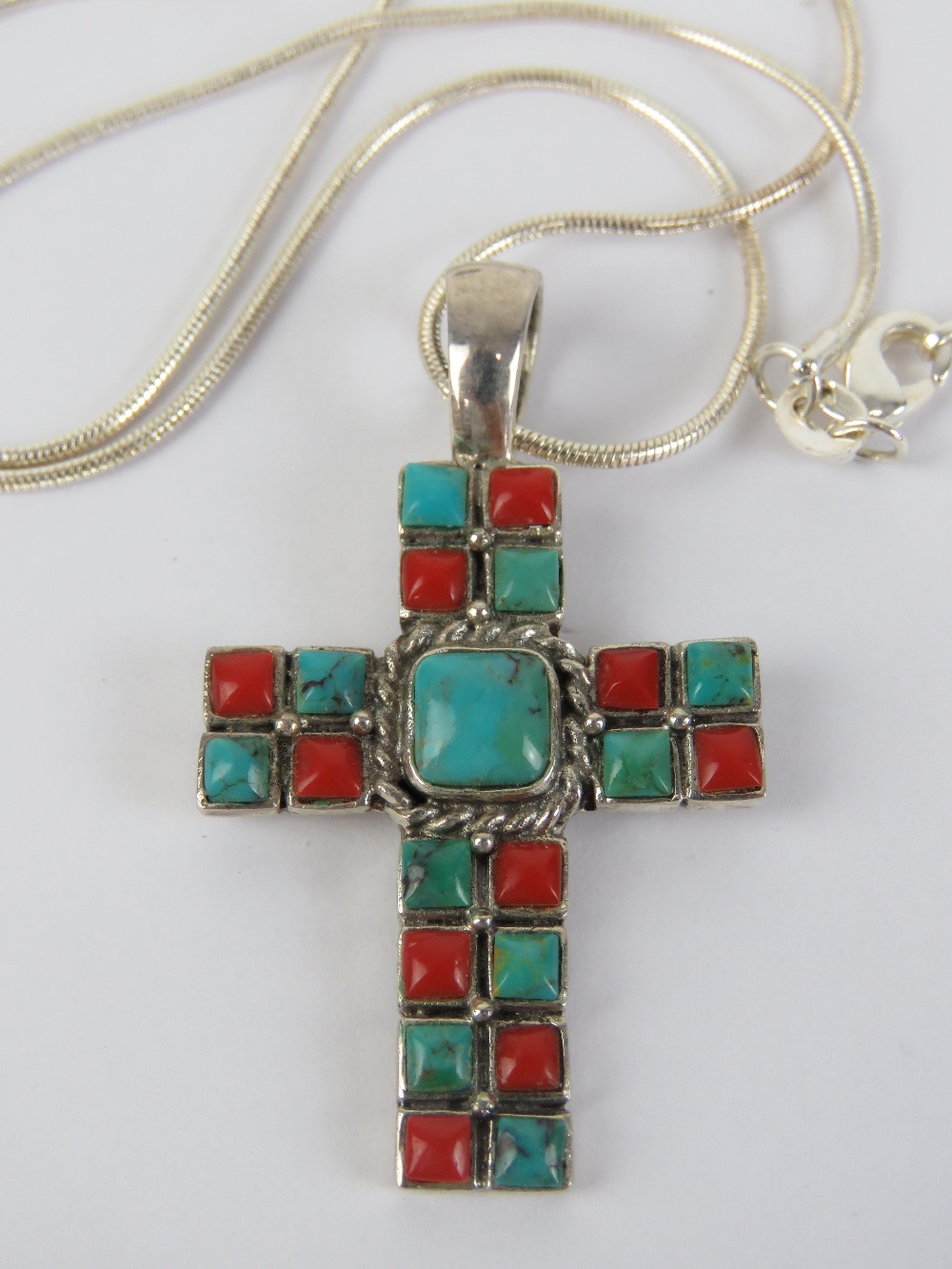 A silver crucifix set with faux coral an