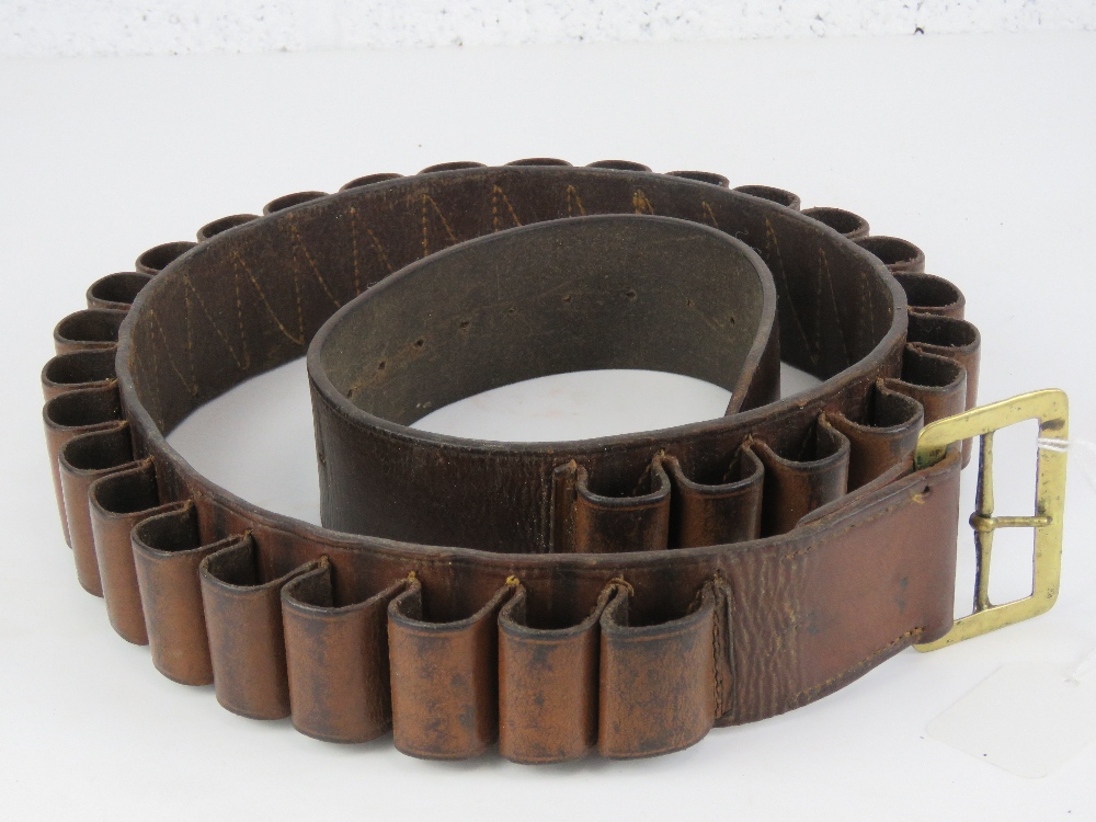 A brown leather shotgun cartridge belt in brown leather with brass buckle.