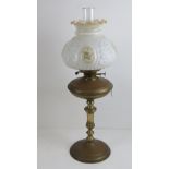 A Victorian oil lamp having brass base and reservoir, milk glass shade and chimney, 68cm high.