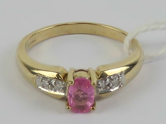 A 9ct gold and pink sapphire ring, the central oval cut sapphire measuring 5.8 x 3.