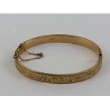 A vintage 9ct gold hinged bangle having floral engraving to front, Chester hallmark,