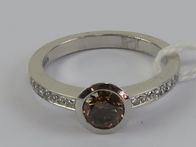 A delightful 18ct white gold and diamond ring having central round cut brilliant champagne diamond