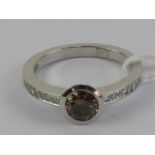 A delightful 18ct white gold and diamond ring having central round cut brilliant champagne diamond