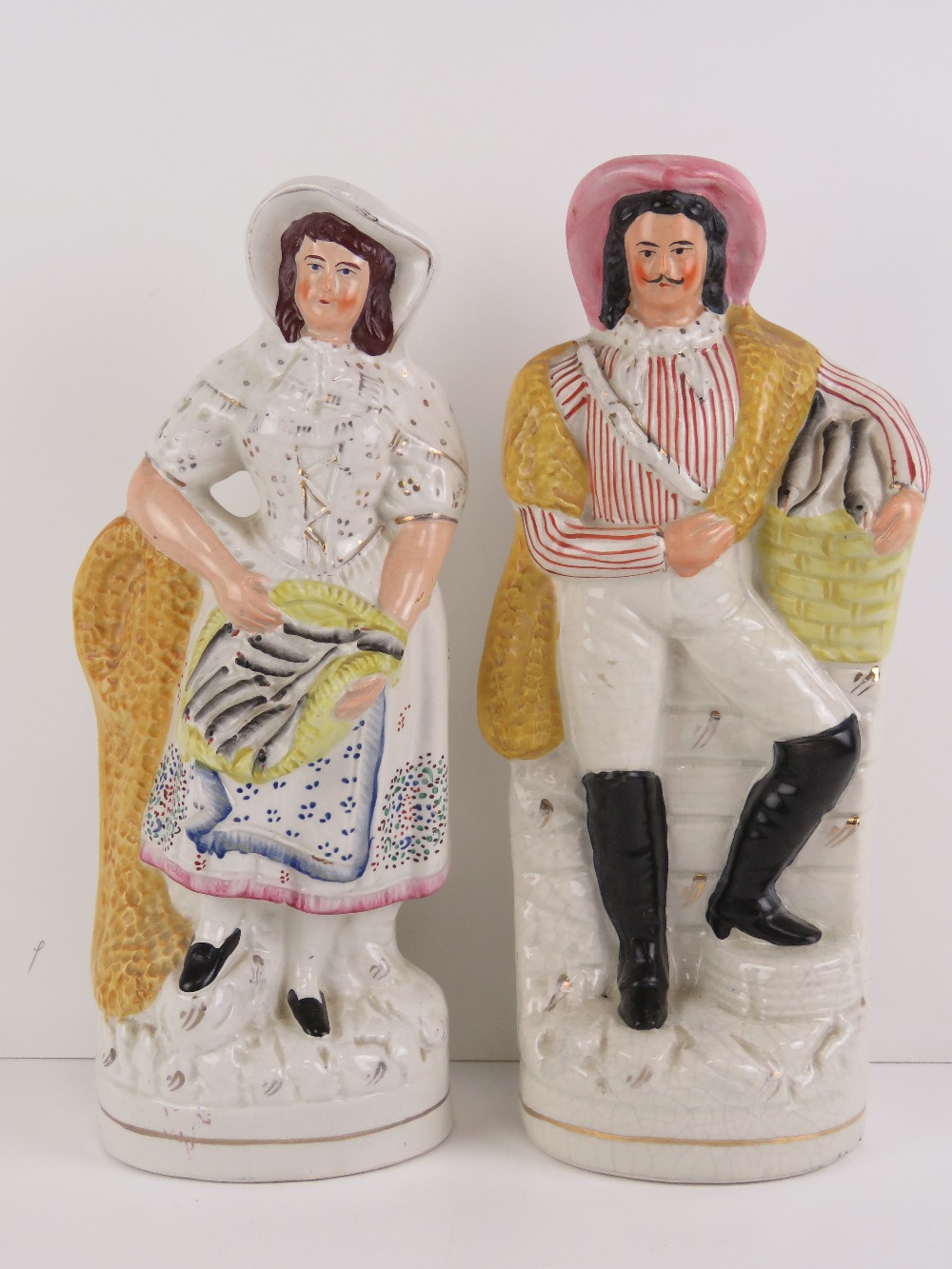 A pair of 19th century Staffordshire flatback figurines being man and woman each holding a woven