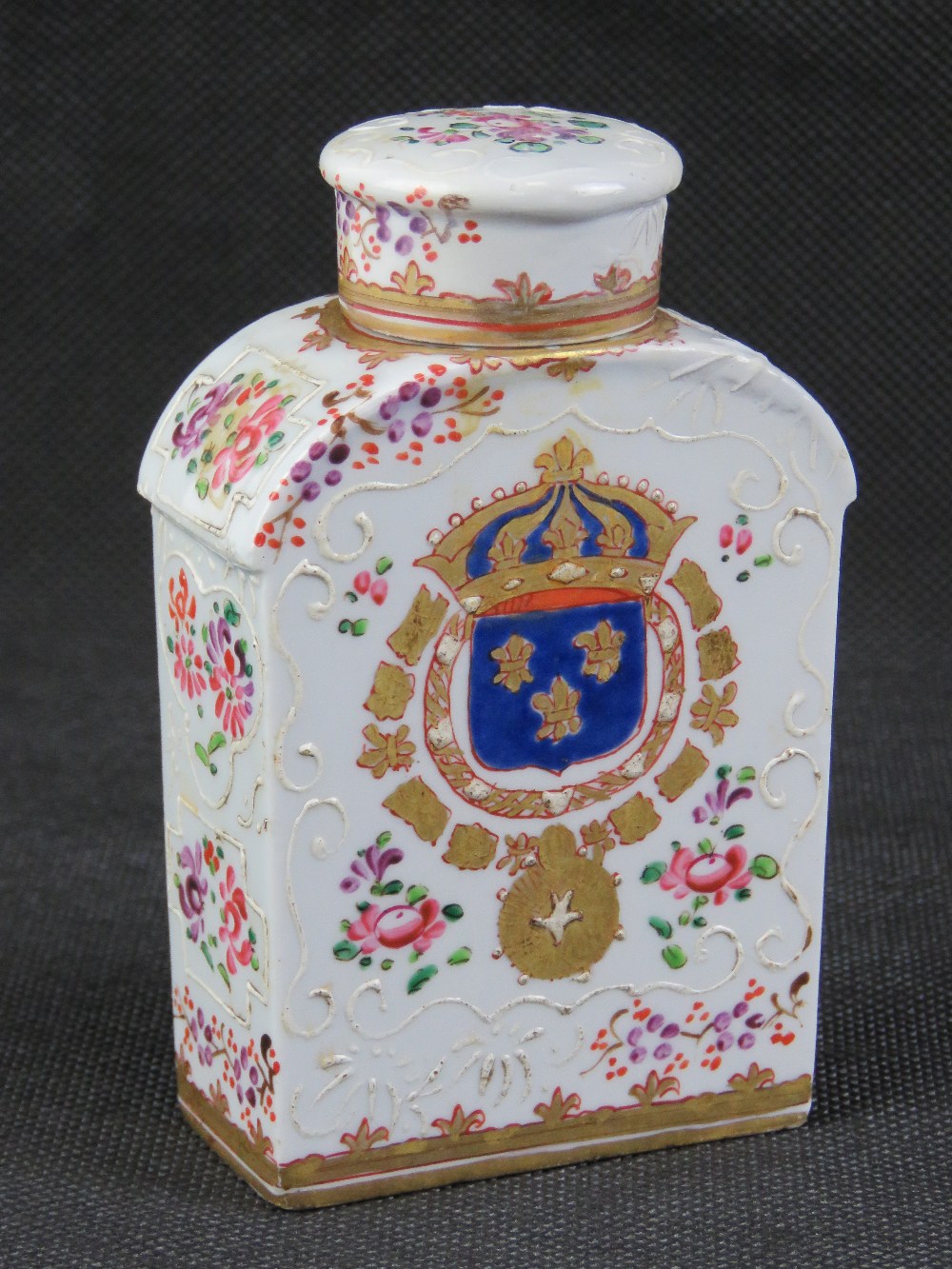 A ceramic lidded flask decorated with floral enamel throughout and bearing heraldic motif to one