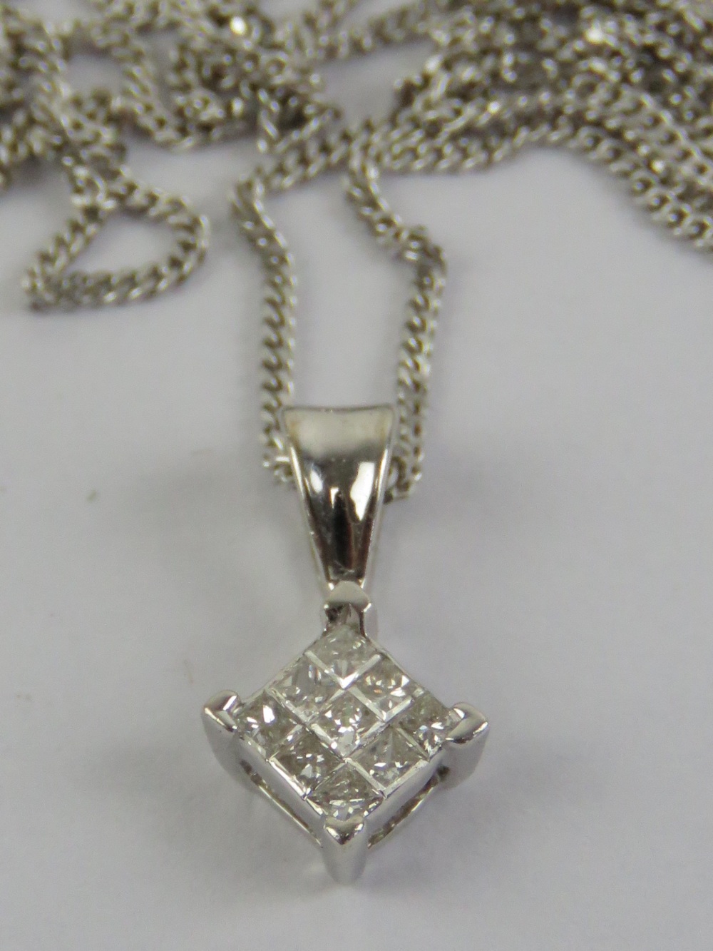 An 18ct white gold and diamond pendant on a 9ct white gold fine chain necklace,