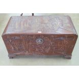 An early 20th century Oriental part carved camphor wood lidded trunk,