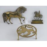 A brass lion ardent trivet together with a small brass door porter in the form of a mounted soldier,