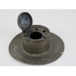 An Arts and crafts pewter inkwell of capstan form, with hinged lid and five quill / pen rest holes,