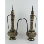 A pair of brass and black ground Arabic coffee pots.