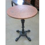 A circular beaten copper pub style table having cast iron quatreform base.