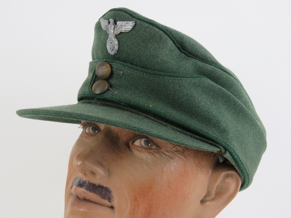 A German M43 cap having eagle and swastika metal badge upon.