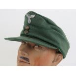 A German M43 cap having eagle and swastika metal badge upon.