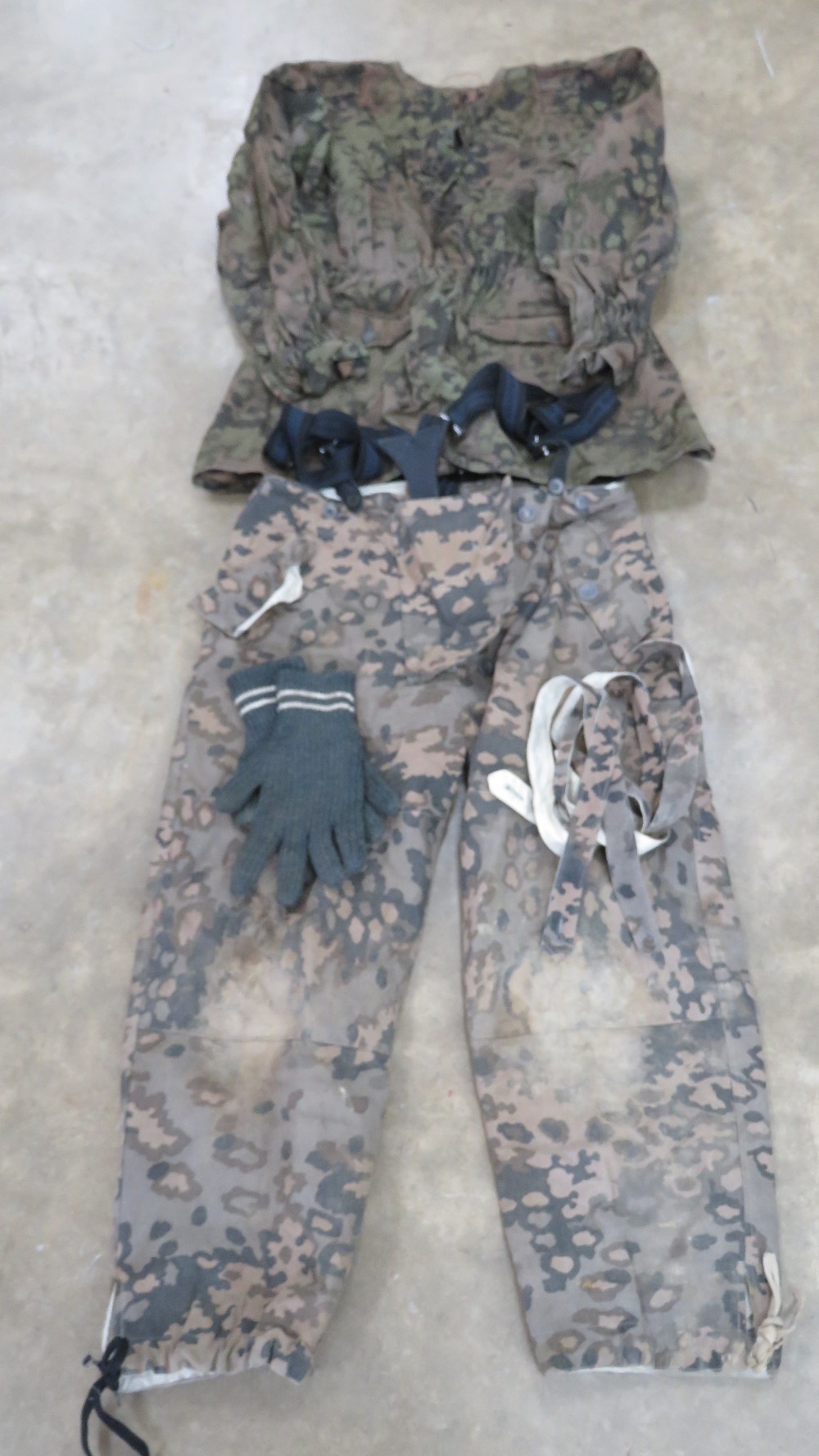 A reproduction WWII German SS camouflage jacket with camouflage Y straps, gloves and trousers.