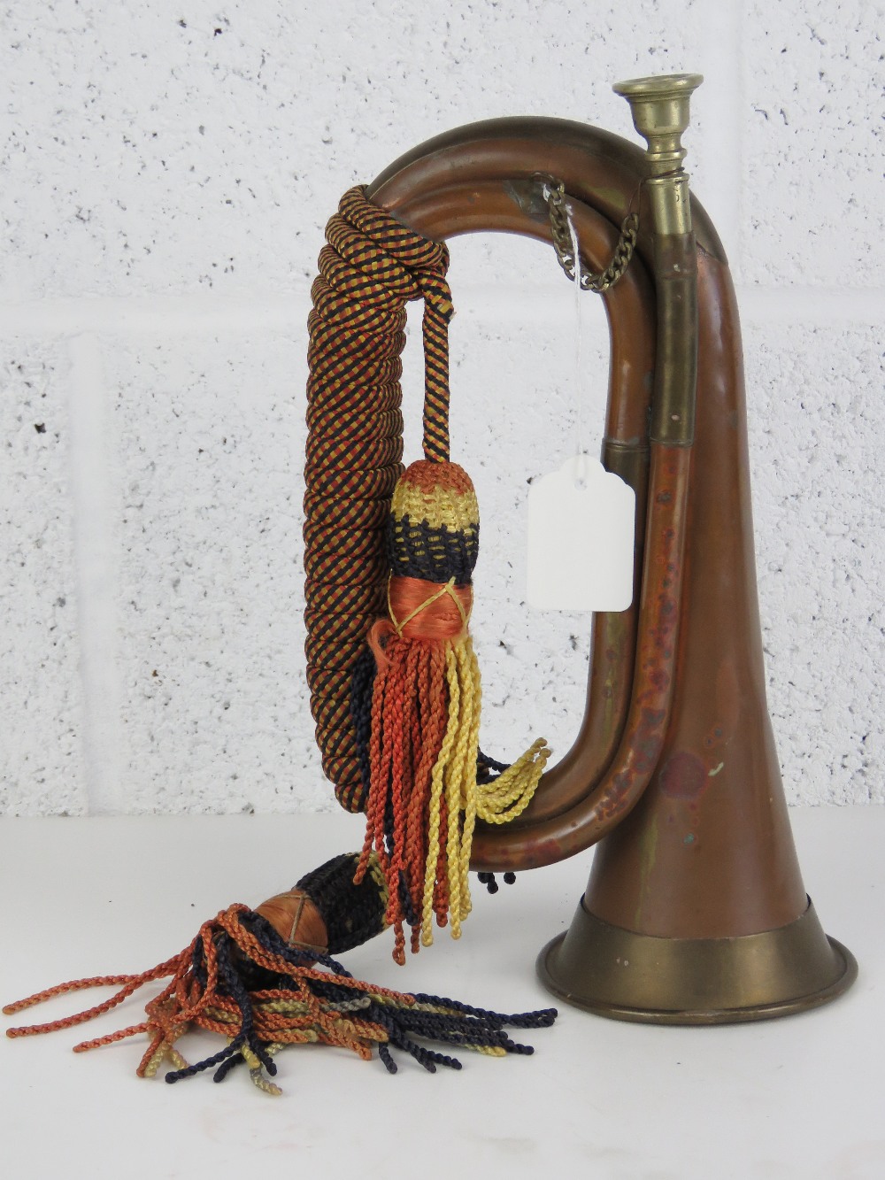 A copper and brass military bugle complete with braided cord and silvered mouthpiece.