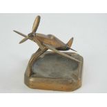 A brass smokers receptacle having Spitfire model over with rotating propeller, 15cm wingspan.