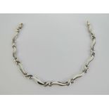 A 9ct white gold atriculated bracelet having cross and wave design panels, 19cm in length,