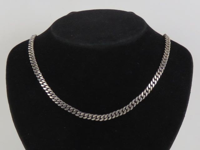 A heavy silver flattened curb link chain necklace complete with safety chain,