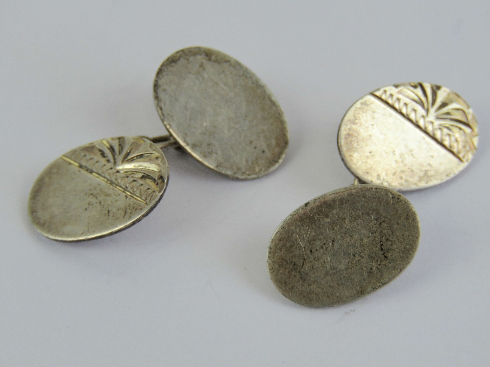 A pair of silver cuff links having half engraved pattern to front, plain back, stamped silver.