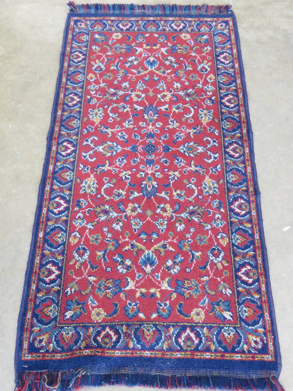 A woollen and silk rug in reds and blues having floral decoration upon 135 x 65cm.