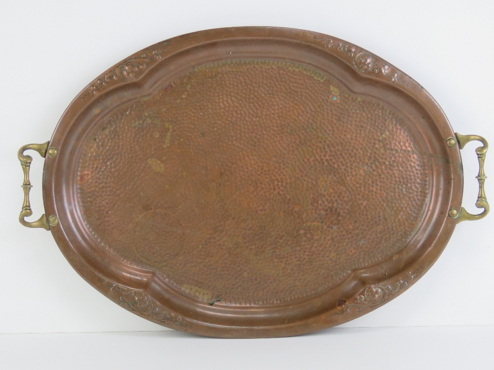 A hand planished copper tray with brass end handles measuring 56cm wide.